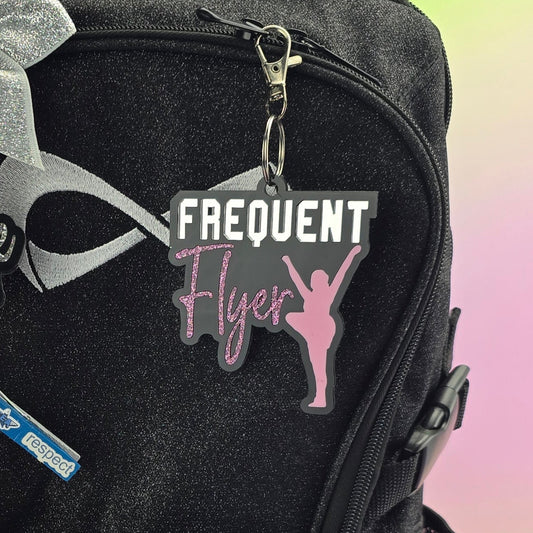 Black bag with various items including a pink hair clip and ruler on a colorful gradient background