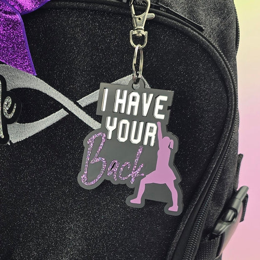Black backpack with decorative keychains on a gradient background