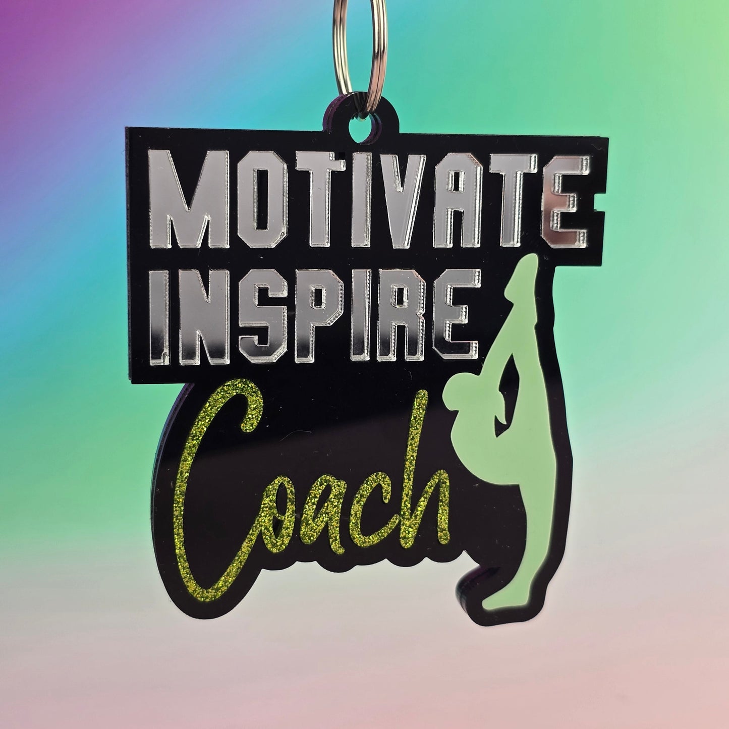Keychain with motivational text 'Motivate Inspire Coach' on a colorful gradient background