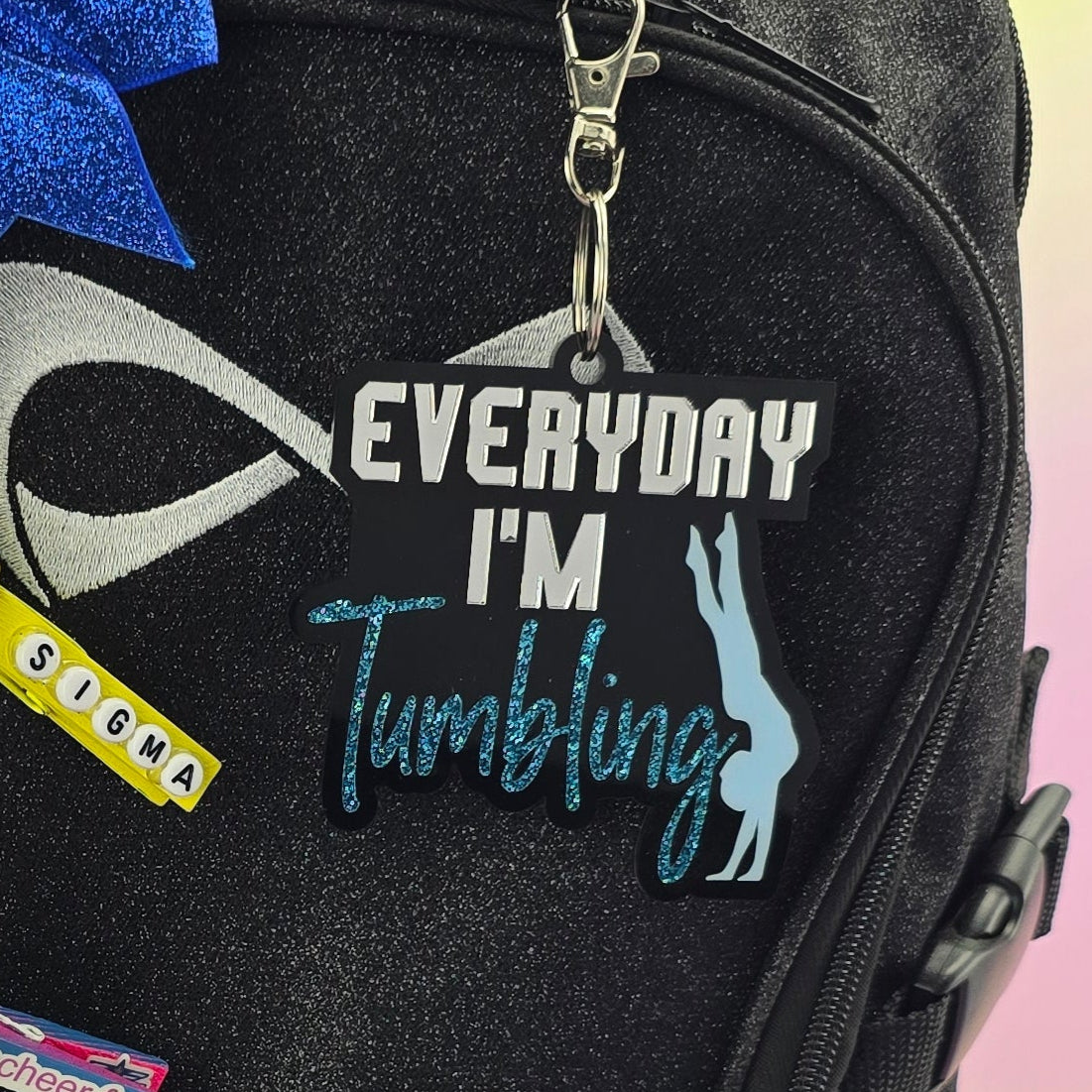 Black backpack with various items attached on a gradient background